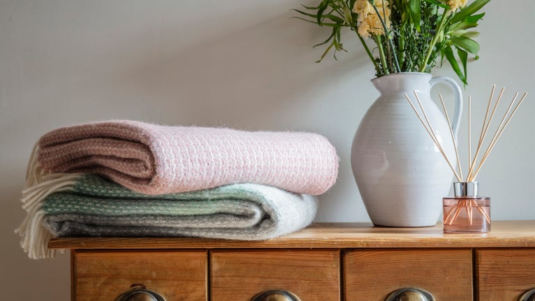 Throws stacked on a cupboard with vase